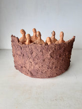 Male nude ceramic sculpture with seven figurines in terracotta on a rust colored curved plinth