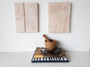 Pair of embossed ceramic wall plaques in pale terracotta and white, pastel textured sculptures