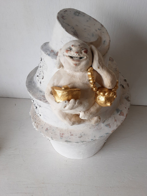 Laughing Buddha sculpture, white ceramic figure with auspicious gold objects on spiral plinth, Buddhist deity