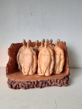 Male nude ceramic sculpture with seven figurines in terracotta on a rust colored curved plinth