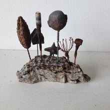 Rustic sculpture with seven recycled and ceramic objects on a timber plinth, coffee table art