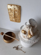 Laughing Buddha sculpture, white ceramic figure with auspicious gold objects on spiral plinth, Buddhist deity