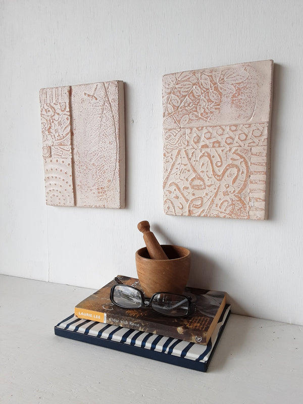 Pair of embossed ceramic wall plaques in pale terracotta and white, pastel textured sculptures