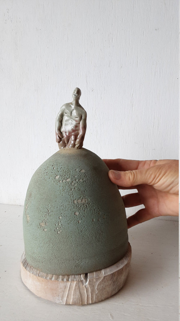 Male statue on mound with timber plinth, ceramic antique look sculpture with celadon green and red glaze