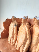 Male nude ceramic sculpture with seven figurines in terracotta on a rust colored curved plinth