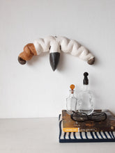 Organic wall sculpture in black white and tan, stylized female reproductive organs in ceramic