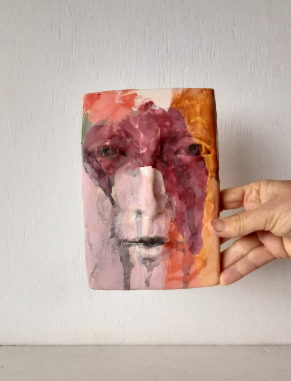 Pink and orange ceramic face sculpture, abstract wall art with multiple colors