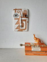 Terracotta orange and white wall sculpture with sawtooth pattern, tribal style decor