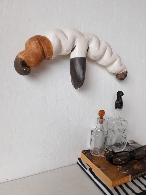 Organic wall sculpture in black white and tan, stylized female reproductive organs in ceramic