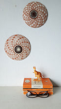 Pair of round white and terracotta ceramic wall plaques with geometric swirling pattern