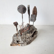 Rustic sculpture with seven recycled and ceramic objects on a timber plinth, coffee table art