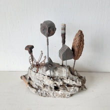 Rustic sculpture with seven recycled and ceramic objects on a timber plinth, coffee table art