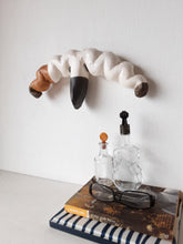 Organic wall sculpture in black white and tan, stylized female reproductive organs in ceramic