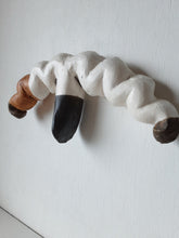 Organic wall sculpture in black white and tan, stylized female reproductive organs in ceramic