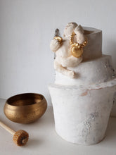 Laughing Buddha sculpture, white ceramic figure with auspicious gold objects on spiral plinth, Buddhist deity