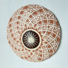 Pair of round white and terracotta ceramic wall plaques with geometric swirling pattern