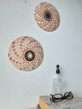 Pair of round white and terracotta ceramic wall plaques with geometric swirling pattern