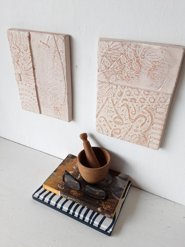 Pair of embossed ceramic wall plaques in pale terracotta and white, pastel textured sculptures