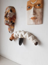 Organic wall sculpture in black white and tan, stylized female reproductive organs in ceramic