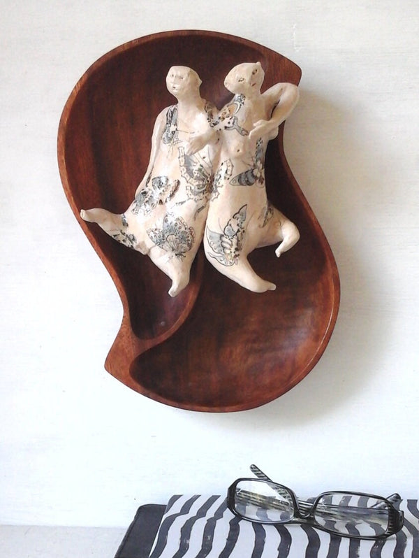 Tattoo wall art of two lovers entwined, sculpture, with reclaimed wood bowl and ceramic figures with butterfly tattoos