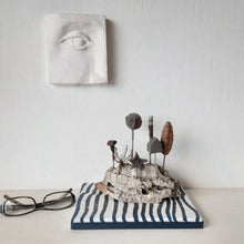 Rustic sculpture with seven recycled and ceramic objects on a timber plinth, coffee table art