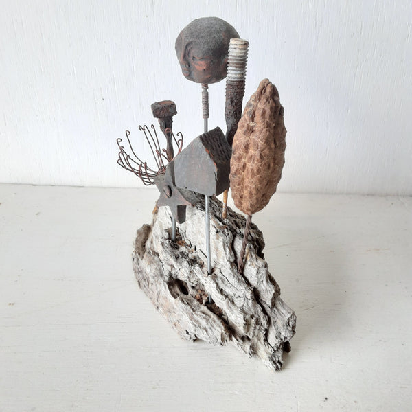 Rustic sculpture with seven recycled and ceramic objects on a timber plinth, coffee table art