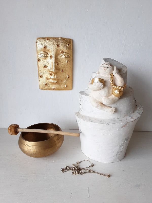 Laughing Buddha sculpture, white ceramic figure with auspicious gold objects on spiral plinth, Buddhist deity