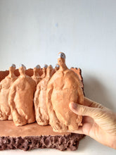 Male nude ceramic sculpture with seven figurines in terracotta on a rust colored curved plinth