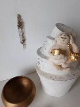 Laughing Buddha sculpture, white ceramic figure with auspicious gold objects on spiral plinth, Buddhist deity