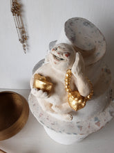 Laughing Buddha sculpture, white ceramic figure with auspicious gold objects on spiral plinth, Buddhist deity