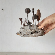 Rustic sculpture with seven recycled and ceramic objects on a timber plinth, coffee table art